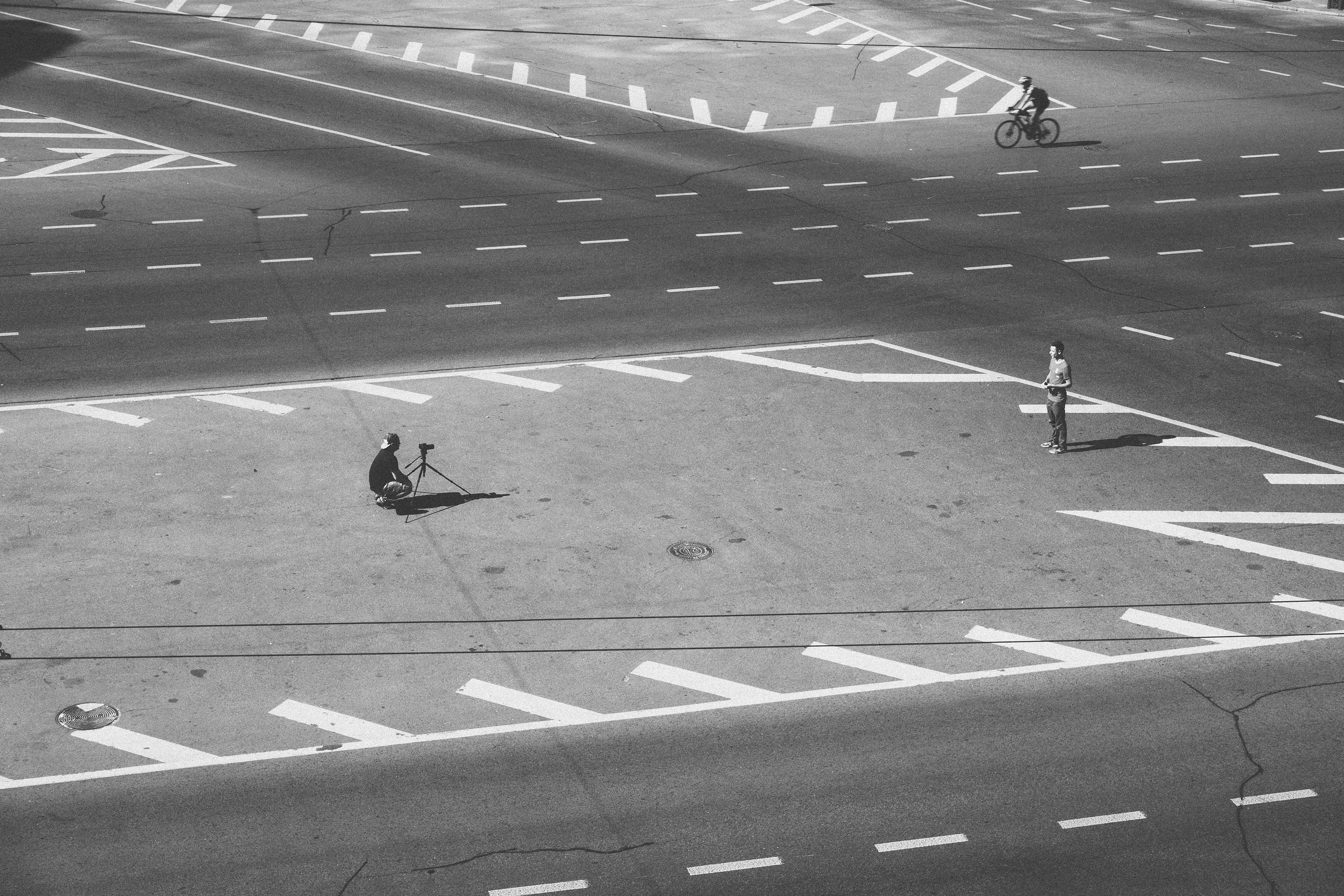 man capturing image of man standing in grayscale photo